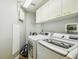 Functional laundry room features white cabinetry, washer, dryer, storage, and ample lighting for added convenience at 14003 Sobrado Dr, Orlando, FL 32837