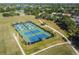 Aerial view of tennis courts, lush green landscaping, and sidewalks in a well-maintained community at 14003 Sobrado Dr, Orlando, FL 32837