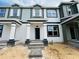 New construction townhome featuring gray and white siding, black trim, and a covered entry with stone steps at 15345 Burgtheater Dr, Winter Garden, FL 34787
