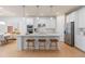 Modern, all-white kitchen with hardwood floors, stainless steel appliances, island with seating and pendant lights at 1536 Groveline Rd, St Cloud, FL 34771