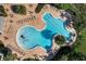 Aerial view of a uniquely shaped outdoor community pool with lounge chairs and lush landscaping at 15477 Blackbead St, Winter Garden, FL 34787