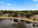 Aerial view of a home beside a pond surrounded by lush greenery and trees at 1552 Whooping Dr, Groveland, FL 34736