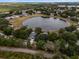 Aerial view of a home near a large pond, surrounded by lush trees and manicured lawns at 1552 Whooping Dr, Groveland, FL 34736