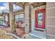 Cozy front porch view highlighting a welcoming red front door with decorative glass and natural accents at 15628 Hidden Lake Cir, Clermont, FL 34711