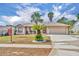 Inviting single-story home with a two-car garage and well-manicured landscaping featuring charming palm trees at 15628 Hidden Lake Cir, Clermont, FL 34711