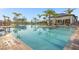 Expansive community pool with modern design, surrounded by palm trees, lounge chairs, and shaded umbrellas at 1596 Moon Valley Dr, Davenport, FL 33896