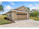 Exterior view of a one-car garage featuring a tan door and lush lawn at 17631 Vista Belle Ct, Montverde, FL 34756