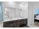 Bathroom featuring double sinks with dark cabinets, white countertop, and an entrance to the bedroom at 2388 Volunteer Ave, Kissimmee, FL 34744