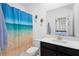 Bright bathroom featuring a white vanity, dark cabinets, and a shower with a vibrant beach-themed curtain at 2388 Volunteer Ave, Kissimmee, FL 34744