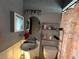 Modest bathroom featuring pedestal sink, round mirror, and storage shelving at 2558 El Capitan Dr, Sanford, FL 32773