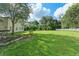 Expansive backyard with lush green grass, trees, garden beds and white fence at 2827 Park Meadow Dr, Apopka, FL 32703