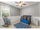 Bedroom room with gray walls, white wainscotting, wood rocking chair and crib with a blue blanket at 2827 Park Meadow Dr, Apopka, FL 32703