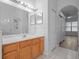 Bright bathroom featuring a wooden vanity, large mirror, glass shower, and hallway to bedroom at 2853 Strand Cir, Oviedo, FL 32765