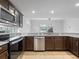 Well-lit kitchen featuring dark wood cabinets, granite countertops, stainless steel appliances and tile floors at 2853 Strand Cir, Oviedo, FL 32765