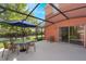 View of the screened-in back patio with an umbrella covered table and sliding glass door to the home at 3001 Red Ginger Rd, Kissimmee, FL 34747