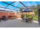 This screened patio has lounge chairs, a hot tub and an umbrella covered table with chairs at 3001 Red Ginger Rd, Kissimmee, FL 34747