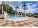Beautiful swimming pool surrounded by palm trees, lounge chairs, and blue umbrellas at 3001 Red Ginger Rd, Kissimmee, FL 34747