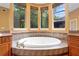 Close-up of large soaking tub with tile surround and multiple windows offering outdoor views at 4107 Gabriella Ln, Winter Park, FL 32792