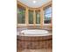 Large soaking tub with brown tile surround and natural light from surrounding windows at 4107 Gabriella Ln, Winter Park, FL 32792