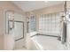 Bright bathroom features a separate glass shower, a soaking tub under a block window, and neutral decor at 441 Hightower Dr, Debary, FL 32713