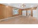 A view of a sunlit bedroom with knotty pine walls, a ceiling fan, and new flooring at 5655 Oak Hollow Ln, Oviedo, FL 32765