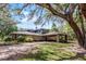 Charming exterior of a home with a porte-cochere surrounded by mature trees and landscaping at 5655 Oak Hollow Ln, Oviedo, FL 32765