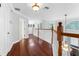 Bright hallway boasts hardwood floors, white railings, and a stylish light fixture at 5655 Oak Hollow Ln, Oviedo, FL 32765