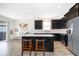 Modern kitchen with dark cabinetry, stainless steel appliances, a white countertop island, and bar stool seating at 6984 Dilly Lake Ave, Groveland, FL 34736