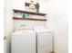 Functional laundry room with white washer and dryer, stylish shelves, and charming decor at 6984 Dilly Lake Ave, Groveland, FL 34736