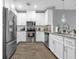 The kitchen has white cabinetry, stainless steel appliances, stone countertops, and hardwood floors at 7573 Laureate Blvd # 1-404, Orlando, FL 32827