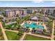Aerial view of community pool, cabanas, tennis court, and colorful apartment buildings at 7573 Laureate Blvd # 1-404, Orlando, FL 32827