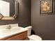 Half bath with a wood vanity, decorative mirror, and dark wall paint, creating a cozy and modern space at 804 Challis Pt, Longwood, FL 32779