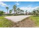 Community sand volleyball court surrounded by lush grass and palm trees on a sunny day at 822 Brunello Dr, Davenport, FL 33897