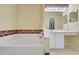 Bathroom featuring a large tub with decorative wallpaper and a vanity with bright lighting and cabinets at 842 Amidon St, Deltona, FL 32725