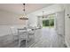 Dining area adjacent to the living room, featuring a modern chandelier and gray wood-look tile flooring at 8420 Corkfield Ave, Orlando, FL 32832
