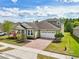 Charming exterior elevation with brick driveway, two-car garage, manicured lawn, and colorful landscaping at 8420 Corkfield Ave, Orlando, FL 32832