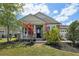 Inviting front porch with stone columns and a well-manicured lawn with colorful landscaping elements at 8420 Corkfield Ave, Orlando, FL 32832