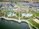 Aerial view of a community showcasing pools, lush landscaping, and a scenic lake at 8943 Coconut Breeze Dr, Kissimmee, FL 34747