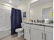 Well-lit bathroom featuring a granite countertop, tiled floor, and shower with a curtain at 8943 Coconut Breeze Dr, Kissimmee, FL 34747