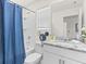 Bright bathroom with granite countertop, white cabinets, and shower with blue curtain at 8943 Coconut Breeze Dr, Kissimmee, FL 34747