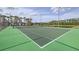Well-maintained tennis court with green surface, surrounded by a fence and tropical landscaping at 8989 Cuban Palm Rd, Kissimmee, FL 34747
