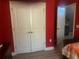 Red bedroom featuring a closet with double doors and white trim, with open ensuite at 1185 Sabine Ln, Kissimmee, FL 34759
