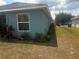 Side yard with a blue house, garden bed and privacy fence at 1185 Sabine Ln, Kissimmee, FL 34759