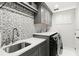 Modern laundry room with gray cabinets, geometric tile backsplash, and stainless steel sink at 10160 Mallard Landings Way, Orlando, FL 32832