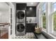 Modern laundry room with stacked washer and dryer, dark cabinets, and patterned tile floor at 104 Cortland Ave, Winter Park, FL 32789