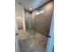 Modern bathroom featuring a tiled walk-in shower with glass door and stone flooring at 1141 Lakeshore Breeze Pl, Kissimmee, FL 34747