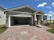 Exterior view of the house featuring an open garage and brick driveway at 1141 Lakeshore Breeze Pl, Kissimmee, FL 34747
