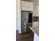 A stainless steel refrigerator is surrounded by white cabinets and light countertops with wood flooring at 1141 Lakeshore Breeze Pl, Kissimmee, FL 34747