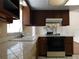 Kitchen with a unique view of the living room stone fireplace, tile countertops and dark wood cabinets at 130 Krider Rd, Sanford, FL 32773