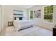 Comfortable bedroom with white bedding, neutral decor, and sun-filled windows overlooking lush landscaping at 1371 Lake Dr, Casselberry, FL 32707